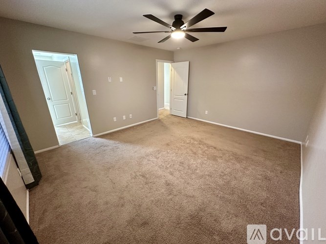 A room with a ceiling fan and carpeted floor.
