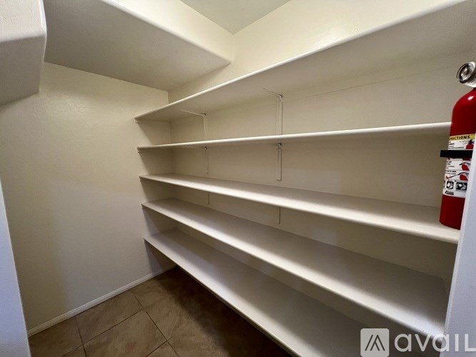 Empty white shelves in a room with a fire extinguisher on the right.