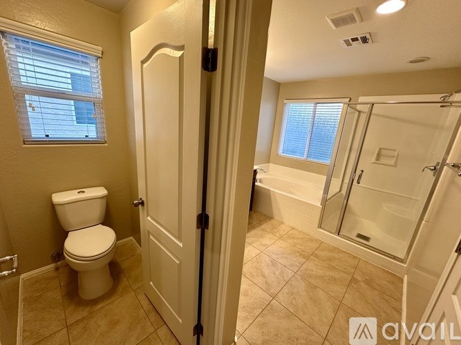 A bathroom with a toilet, a shower, and a window.