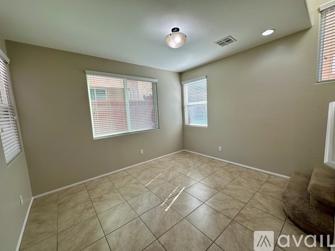A room with beige walls and a tiled floor with a window on the left side.