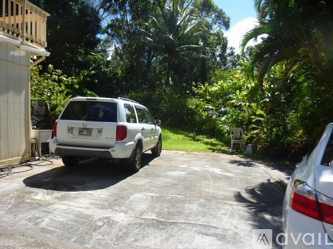 A white car is parked in a driveway.