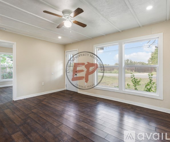 A room with a ceiling fan and wood flooring.
