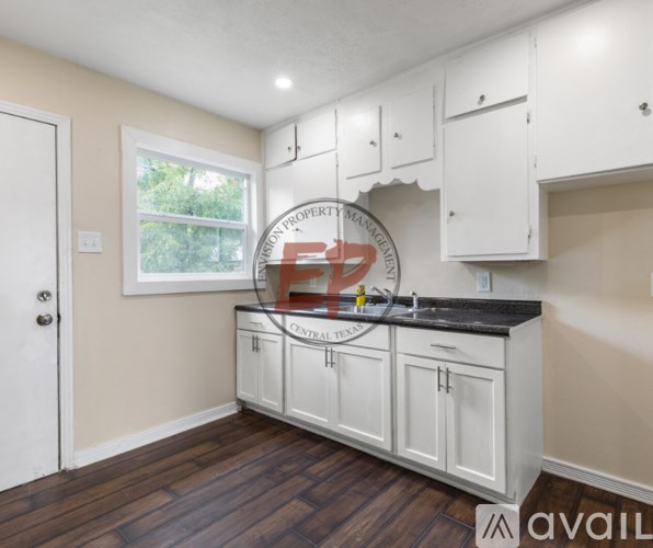 A kitchen with white cabinets and a black countertop.