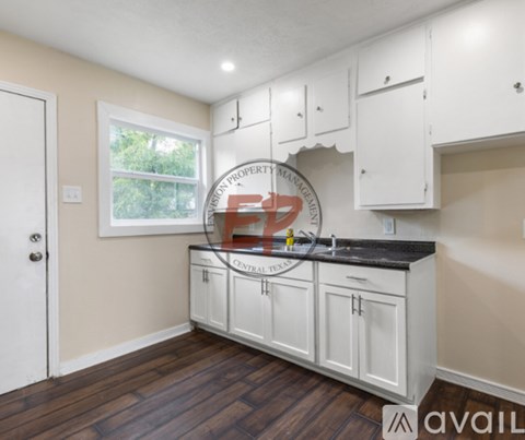A kitchen with white cabinets and a black countertop.