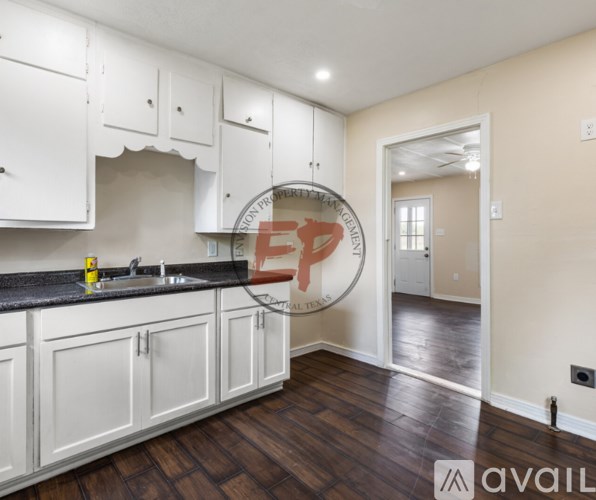 A kitchen with white cabinets and a black countertop.