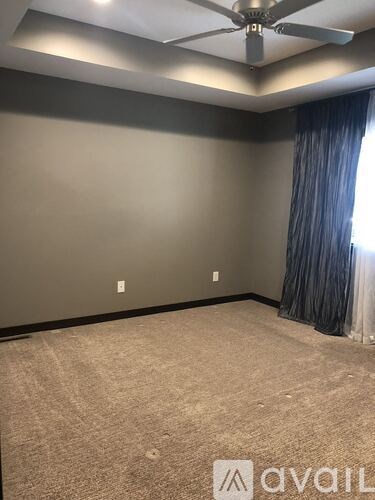 A room with a ceiling fan and carpeted floor.