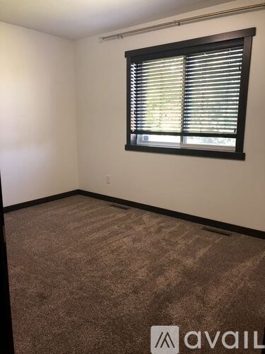 A carpeted room with a window covered in blinds.