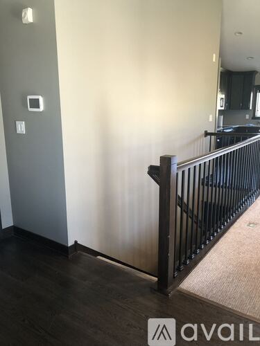 A hallway with a black railing and wooden floors.