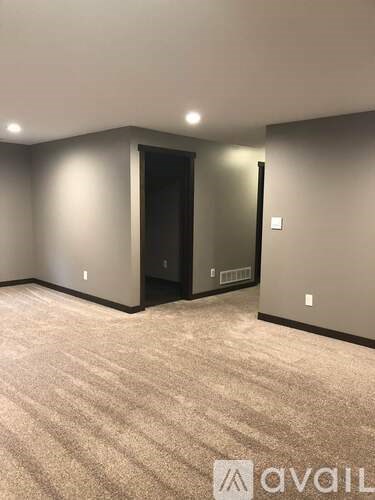 A carpeted room with a door and a wall socket.