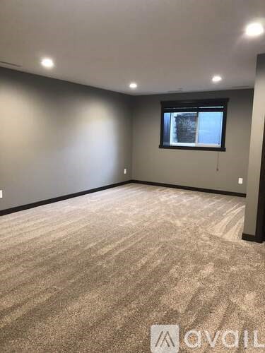 A room with a carpeted floor and a window showing a building outside.