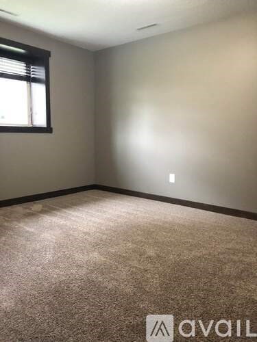 A room with a carpeted floor and a window with blinds.