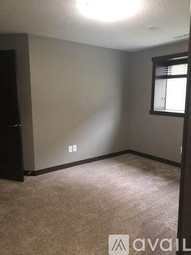 A room with a carpeted floor and a window with blinds.