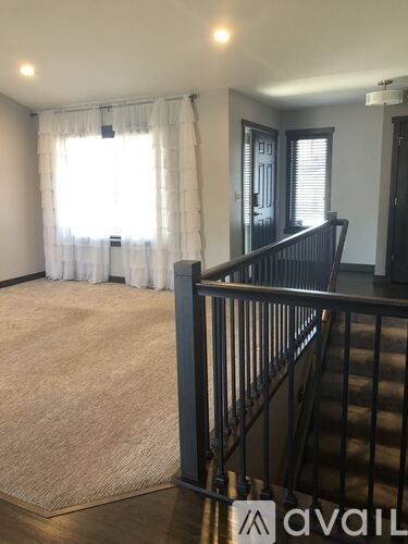 A room with a staircase and a window with curtains.