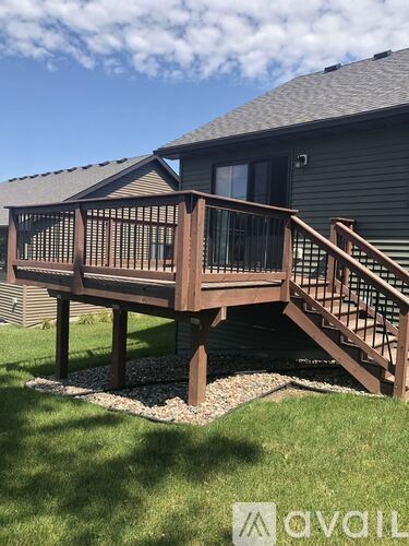 A wooden deck with a staircase leading to a house.