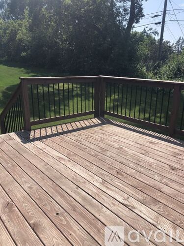 A wooden deck with a railing overlooking a grassy area.