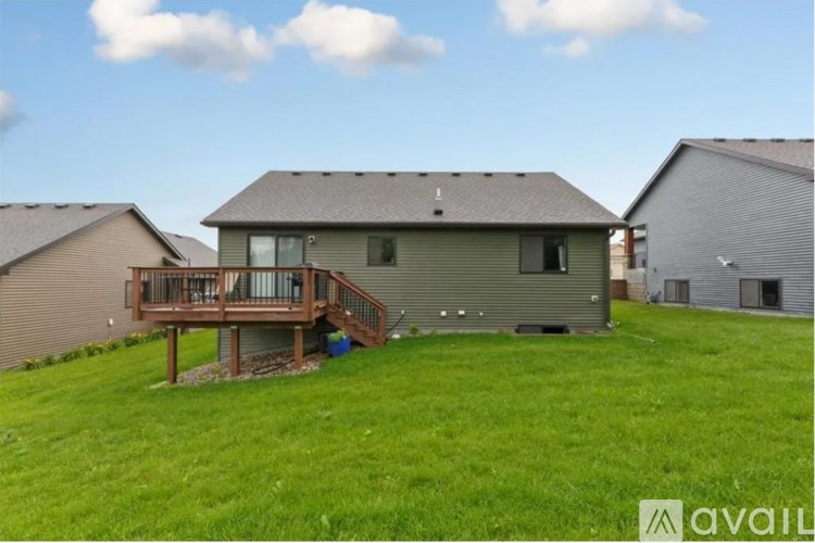 A house with a deck and a green lawn is for sale.