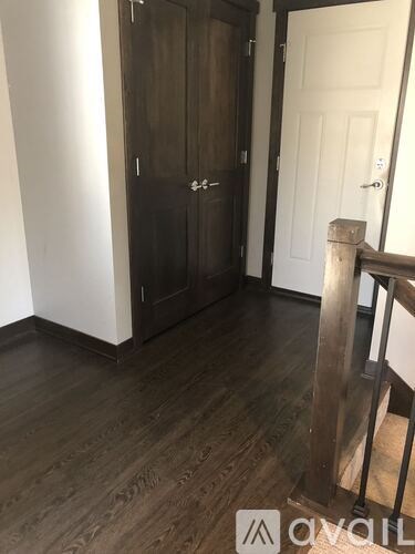 A dark brown wooden wardrobe with a white door is in the corner of a room.