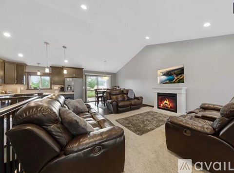 A living room with brown leather couches and a fireplace.