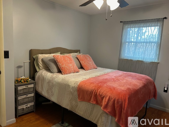 A bedroom with a bed, pillows, and a ceiling fan.