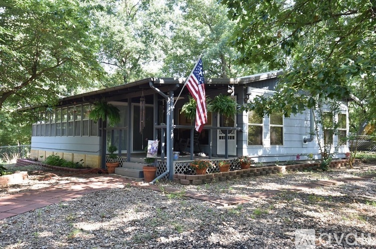 A house with a flag on the porch is surrounded by trees.