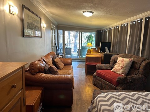 A living room with a brown leather couch and a red chair.