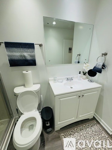 A white toilet with a roll of toilet paper on top of it.