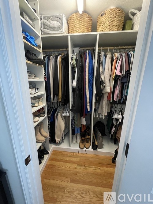 A white closet with clothes and shoes on shelves and hangers.