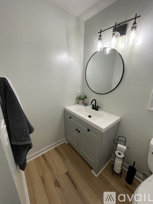A bathroom with a white sink and a round mirror.