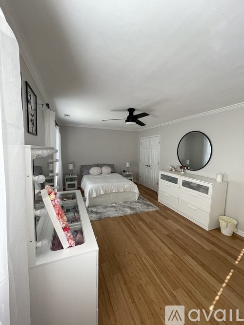 A bedroom with a bed, dresser, mirror, and ceiling fan.