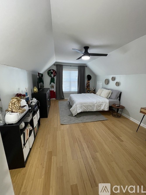 A bedroom with a bed, a ceiling fan, and a wooden floor.