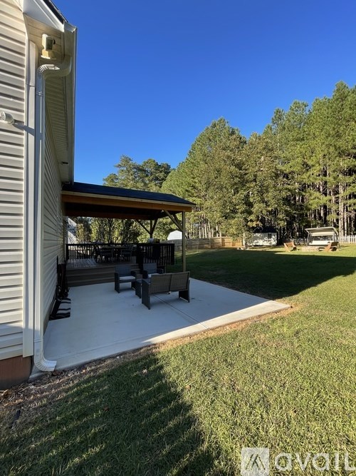 A covered patio area with a table and chairs is attached to a house.