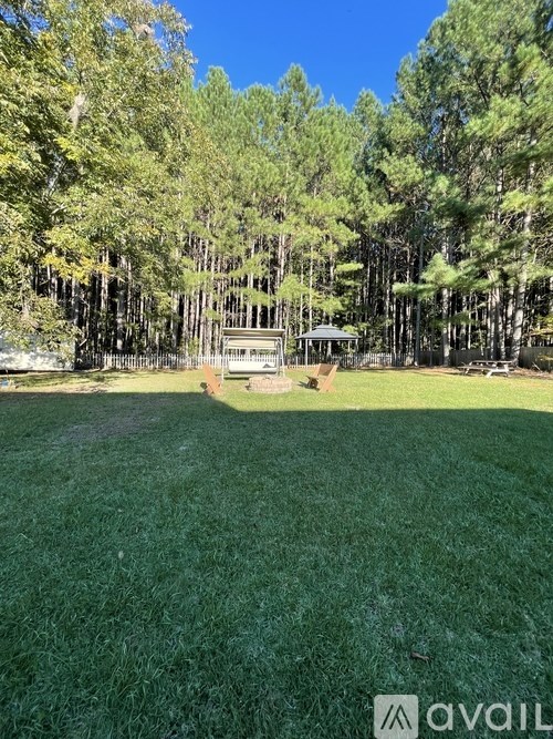 A grassy area with a gazebo surrounded by trees.