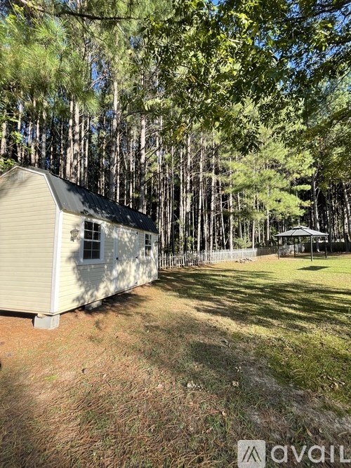 A small house is surrounded by trees in a wooded area.
