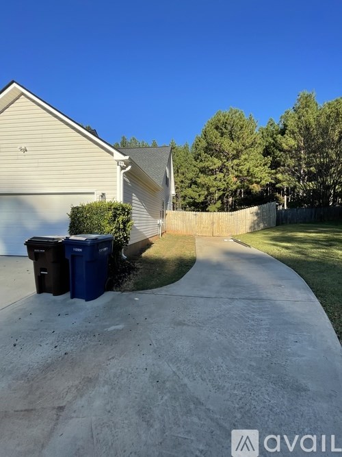 A house with a driveway and two trash bins.