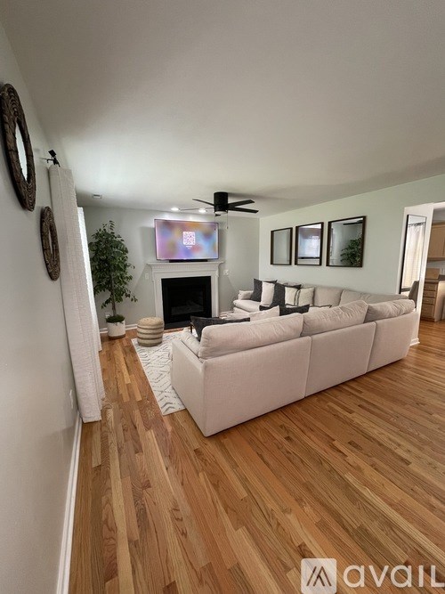 A living room with a white couch and a flat screen TV mounted on the wall.