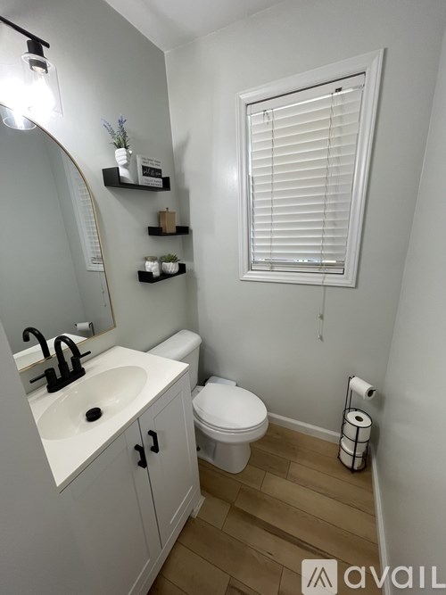A bathroom with a toilet, sink, and mirror.
