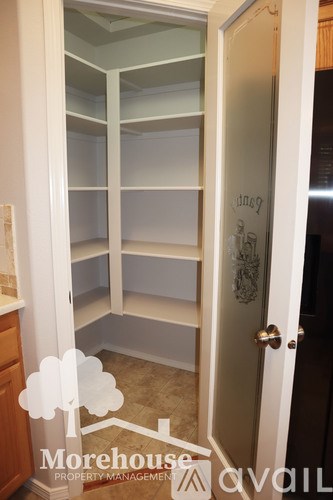 A white door with a glass window is open to a room with shelves.