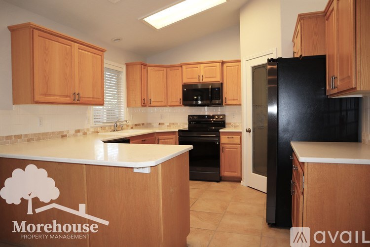 A kitchen with wooden cabinets and a black refrigerator.