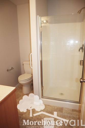 A white toilet sits in a bathroom next to a walk-in shower.