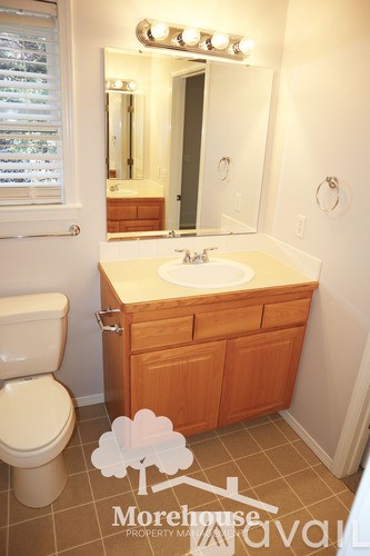 A white sink in a wooden cabinet in a bathroom.