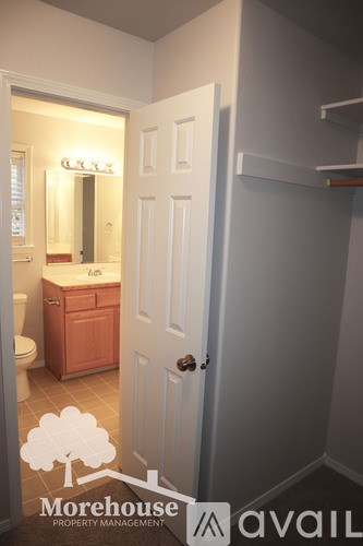 A white door is open to a bathroom with a white sink and a white cabinet.