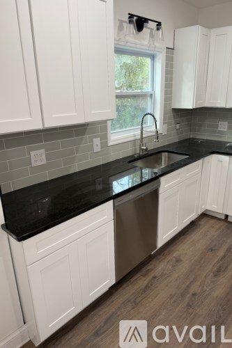 A kitchen with white cabinets and a black countertop.