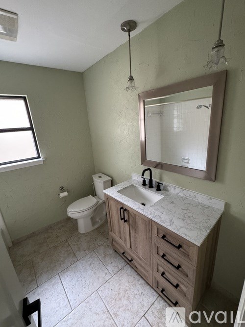 A bathroom with a toilet, sink, and mirror.