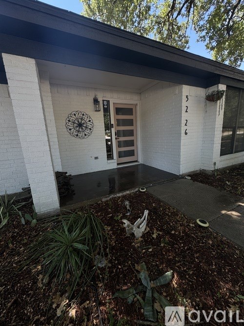 A white house with a black roof and a door with a clock on the wall.