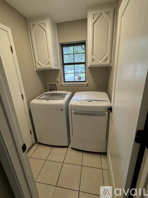 A small laundry room with a window and two washing machines.