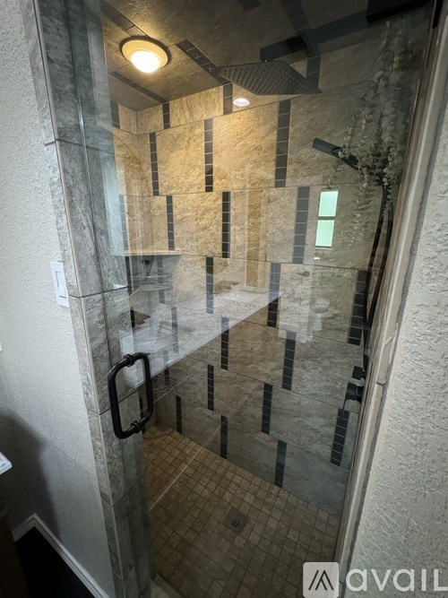A bathroom with a glass shower door and tiled floor.