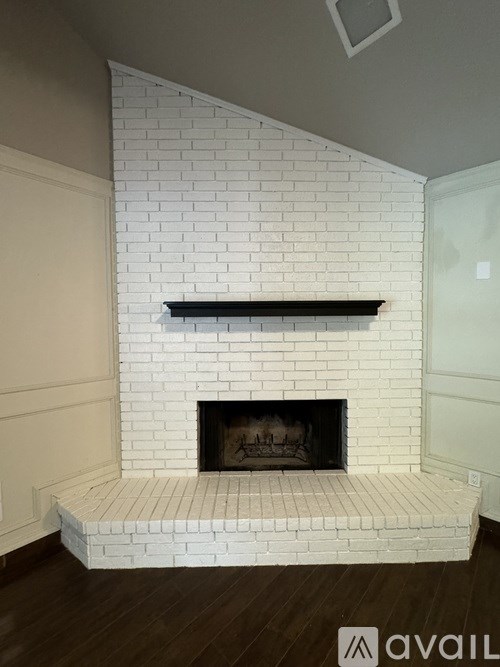 A white brick fireplace with a black mantle.