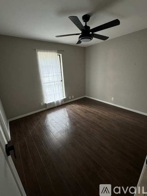 A room with a ceiling fan and wooden flooring.