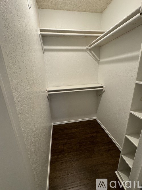 A white closet with shelves and a wooden floor.
