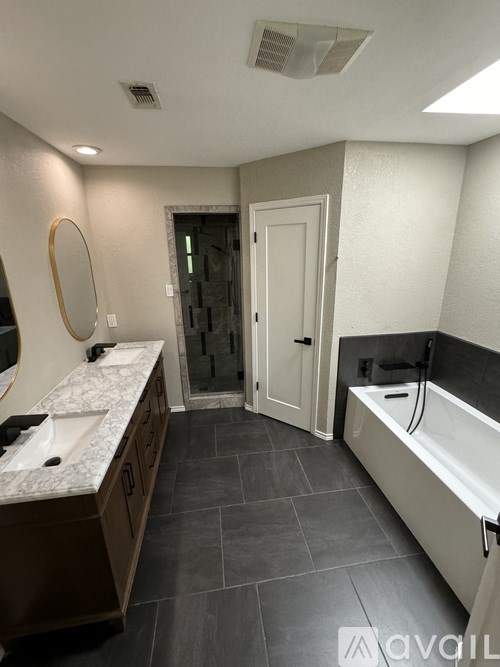 A bathroom with a tub, sink, and mirror.